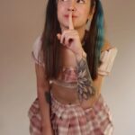 Pretty teen girl in plaid skirt with her finger to her lip.