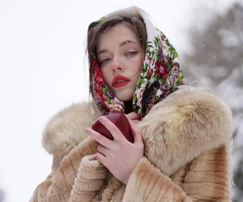 Young beauty in head scarf and fur coat in a wintry snow scene.