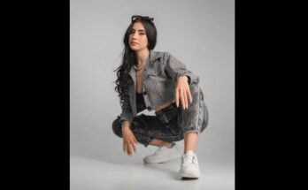 Beautiful Hispanic woman squatting in denim jeans and jacket.