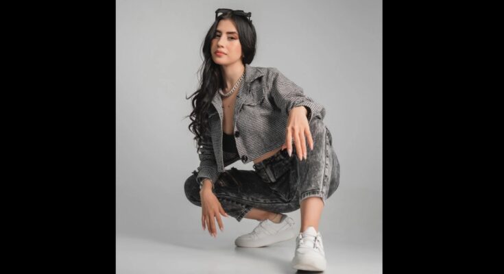 Beautiful Hispanic woman squatting in denim jeans and jacket.